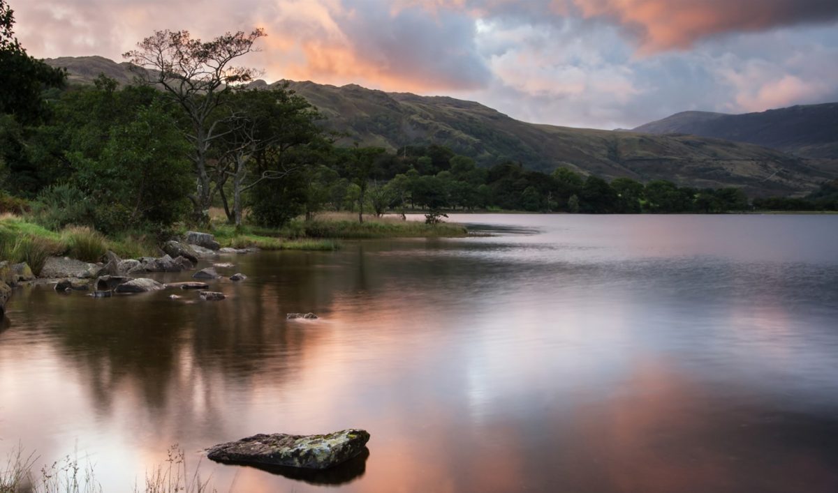 Lake Gwynant at sunset, with calm waters reflecting the surrounding hills
