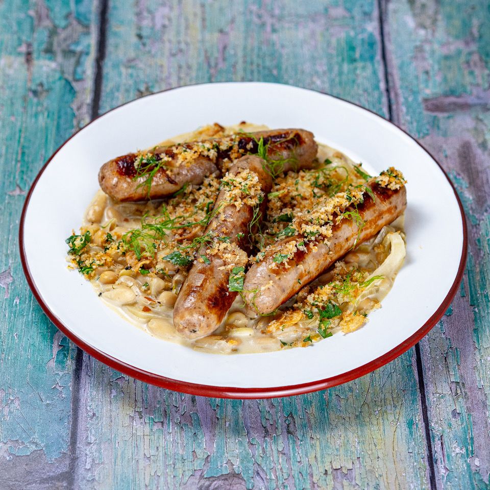 Grilled sausages on a creamy bean base topped with herbs and breadcrumbs