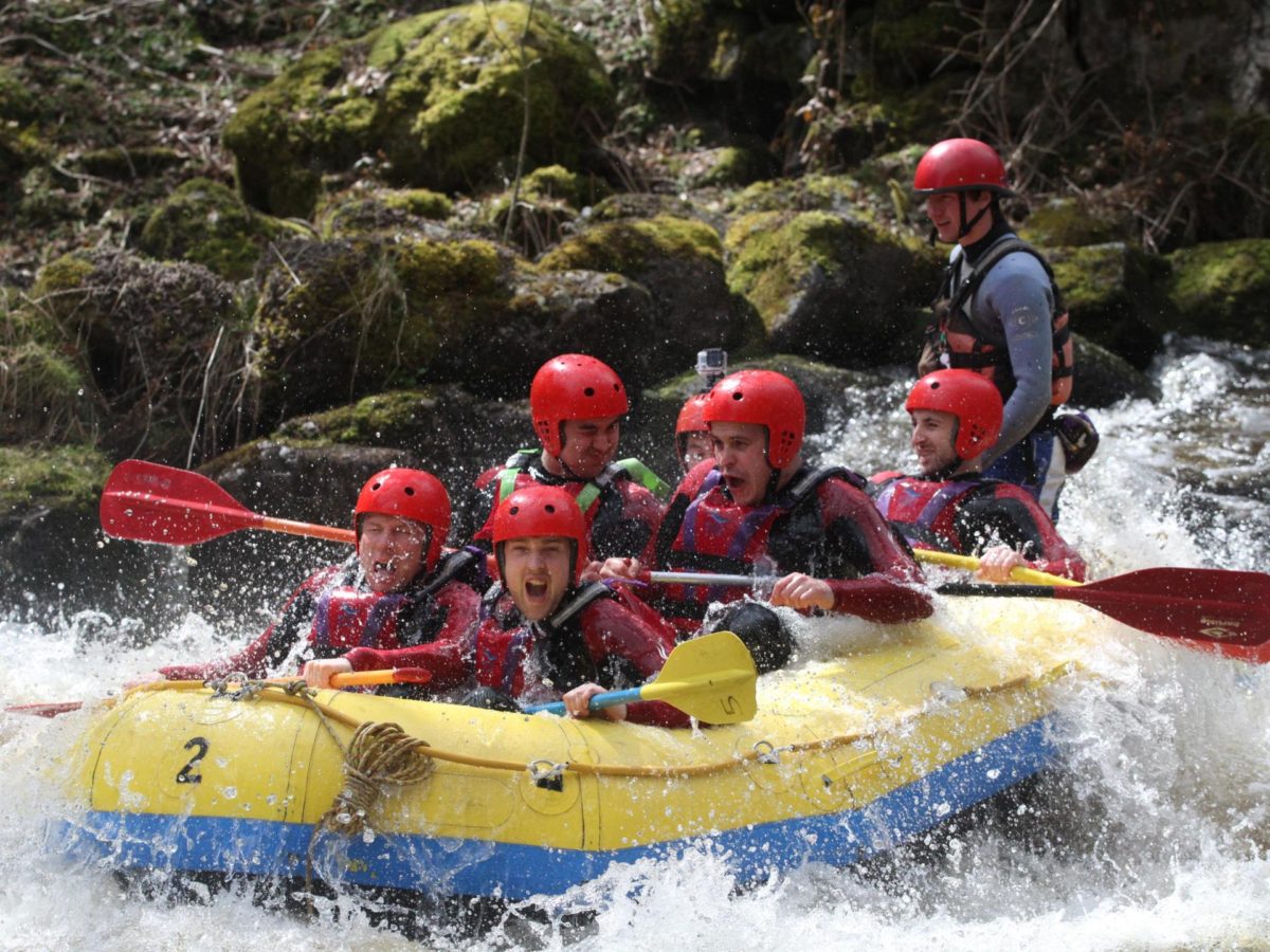 Group white water rafting on a fast-flowing river in North Wales
